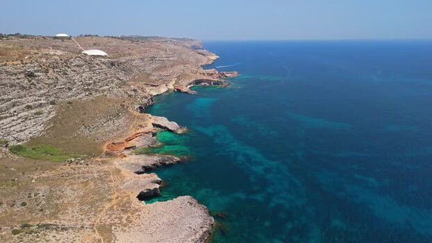 Aerial view of Ghar Lapsi bay Malta with cliffs and turquoise water below Aerial view of Ghar Lapsi bay Malta with cliffs and turquoise water below