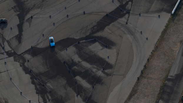 Aerial view of a blue car driving on a paved test track marked with tires and white lines in Hockenheim Baden Wurttemberg Germany. Aerial view of a blue car driving on a paved test track marked with tires and white lines in Hockenheim Baden Wurttemberg Germany.