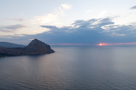 Aerial view of Riserva Naturale Orientata dello Zingaro at sunset with dramatic cliffs meeting the calm sea under a soft sky in San Vito Lo Capo Sicilia Italy. Aerial view of Riserva Naturale Orientata dello Zingaro at sunset with dramatic cliffs meeting the calm sea under a soft sky in San Vito Lo Capo Sicilia Italy.