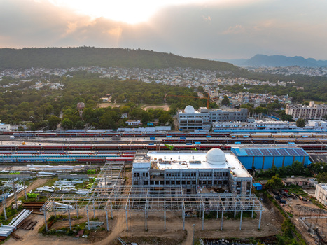 Aerial view of the railway station construction site with a white dome and steel framework trains on tracks and a hilly background in Udaipur Rajasthan India. Aerial view of the railway station construction site with a white dome and steel framework trains on tracks and a hilly background in Udaipur Rajasthan India.