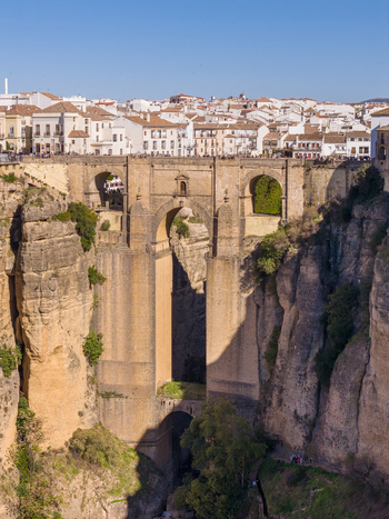 Aerial view of the historic Puente Nuevo bridge spanning the deep El Tajo gorge with white buildings of the old town in the background in Ronda Andalusia Spain. Aerial view of the historic Puente Nuevo bridge spanning the deep El Tajo gorge with white buildings of the old town in the background in Ronda Andalusia Spain.