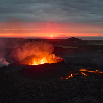 Aerial view of a volcanic eruption with glowing lava flowing from a crater at sunset in Iceland. Aerial view of a volcanic eruption with glowing lava flowing from a crater at sunset in Iceland.
