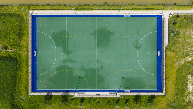 Aerial view of the H.C. Rijnvliet field hockey pitch featuring green turf and blue borders surrounded by lush grass in Utrecht Utrecht Netherlands.