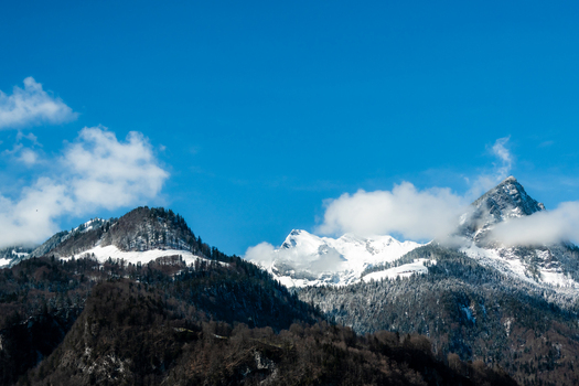 View of snow dusted peaks pierce the vibrant blue sky a tranquil scene unfolding from the train window Train from Lucerne to Interlaken Switzerland. View of snow dusted peaks pierce the vibrant blue sky a tranquil scene unfolding from the train window Train from Lucerne to Interlaken Switzerland.