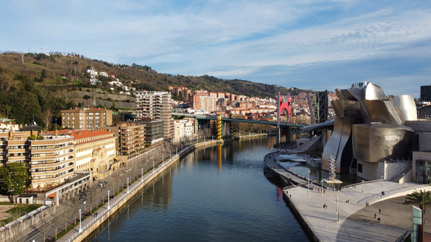 Aerial view of the Guggenheim Museum Bilbao along the Nervion River featuring its iconic titanium architecture surrounding urban buildings and a bridge in Bilbao Basque Country Spain. Aerial view of the Guggenheim Museum Bilbao along the Nervion River featuring its iconic titanium architecture surrounding urban buildings and a bridge in Bilbao Basque Country Spain.