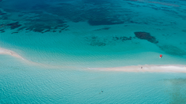 Aerial view of Los Roques archipelago featuring a white sandbar surrounded by crystal clear turquoise water and a small boat in Los Roques Dependencias Federales Venezuela. Aerial view of Los Roques archipelago featuring a white sandbar surrounded by crystal clear turquoise water and a small boat in Los Roques Dependencias Federales Venezuela.