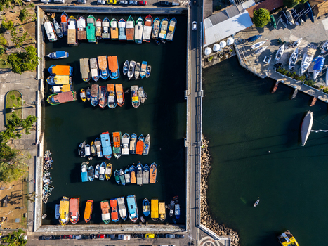 Aerial view of Quadrado da Urca marina featuring colorful fishing boats docked in rows along concrete piers with a road alongside in Rio de Janeiro Rio de Janeiro Brazil.