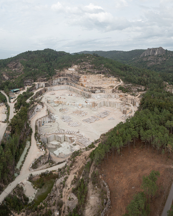 Aerial view of the Cantera Porrino granite quarry showing large stone blocks excavation terraces surrounding pine forests and winding access roads in O Porrino Pontevedra Spain. Aerial view of the Cantera Porrino granite quarry showing large stone blocks excavation terraces surrounding pine forests and winding access roads in O Porrino Pontevedra Spain.