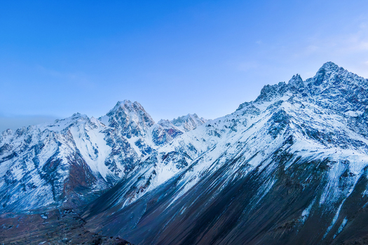 Aerial view of snow capped peaks pierce the crisp clear sky their rugged textures contrasting against the smooth ethereal blue Hunza Nagar Gilgit Pakistan. Aerial view of snow capped peaks pierce the crisp clear sky their rugged textures contrasting against the smooth ethereal blue Hunza Nagar Gilgit Pakistan.
