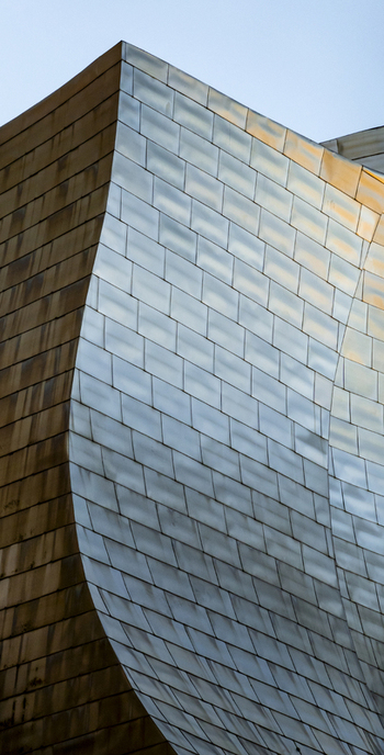 View of the curved titanium panels of the Guggenheim Museum Bilbao with metallic reflections and architectural details in Bilbao Euskadi Spain. View of the curved titanium panels of the Guggenheim Museum Bilbao with metallic reflections and architectural details in Bilbao Euskadi Spain.