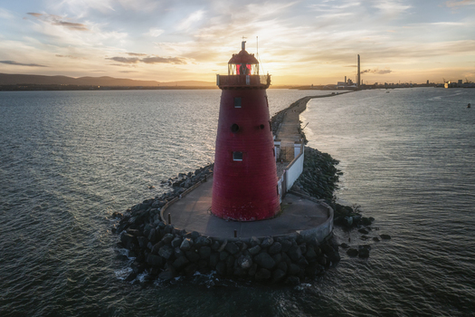 Aerial view of Poolbeg Lighthouse the iconic red tower at the end of the Great South Wall with the calm sea and sunset sky over the horizon Dublin County Dublin Ireland.