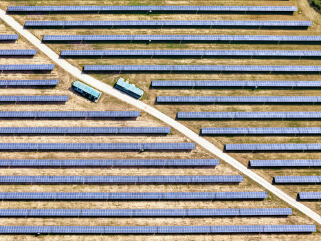 Aerial view of a large solar farm with rows of photovoltaic panels and a white access road in Torrazza Piemonte Piemonte Italy. Aerial view of a large solar farm with rows of photovoltaic panels and a white access road in Torrazza Piemonte Piemonte Italy.