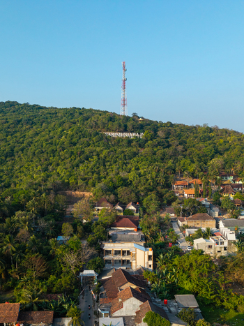 Aerial view of the Karimunjawa sign on a lush green hillside with a tall communication tower overlooking a residential area Karimunjawa Central Java Indonesia. Aerial view of the Karimunjawa sign on a lush green hillside with a tall communication tower overlooking a residential area Karimunjawa Central Java Indonesia.