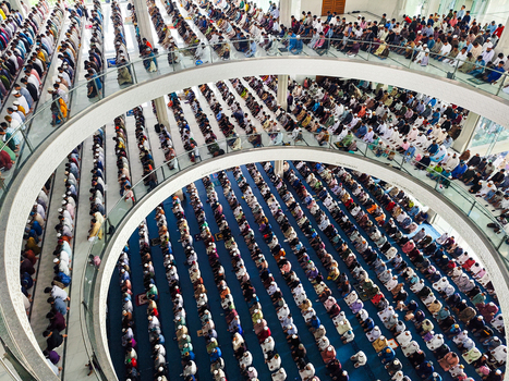 Dhaka Bangladesh 19 June 2026 Aerial view of a large congregation of people praying inside a modern mosque with multi level circular balconies and blue carpets.