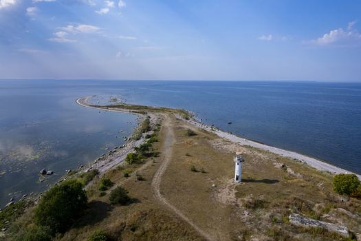 Aerial view of the Neeme lighthouse standing on a narrow rocky coastal peninsula surrounded by the blue waters of the Baltic Sea in Neeme Harju County Estonia.