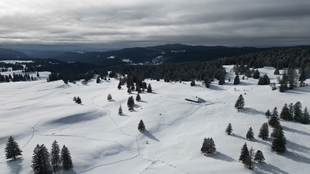 Aerial view of the snowy expanse meeting the dark forest under a cloudy sky Mijoux Auvergne Rhône Alpes France. Aerial view of the snowy expanse meeting the dark forest under a cloudy sky Mijoux Auvergne Rhône Alpes France.