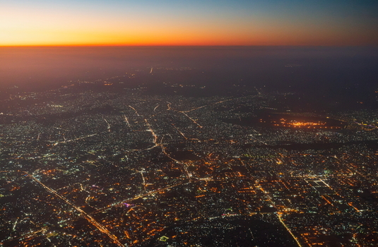 Aerial view of the sprawling urban landscape of Karachi at night with dense city lights illuminating the streets and buildings under a twilight sky Karachi Sindh Pakistan.