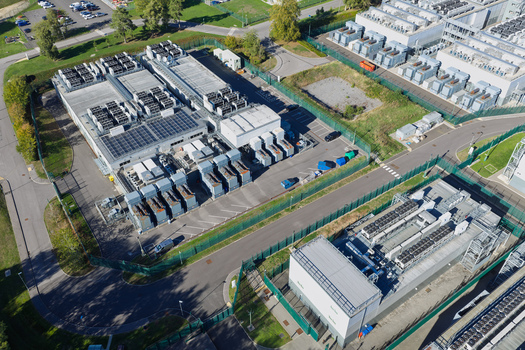 Aerial view of a data center facility featuring rooftop solar panels cooling units and security fencing in the United Kingdom.