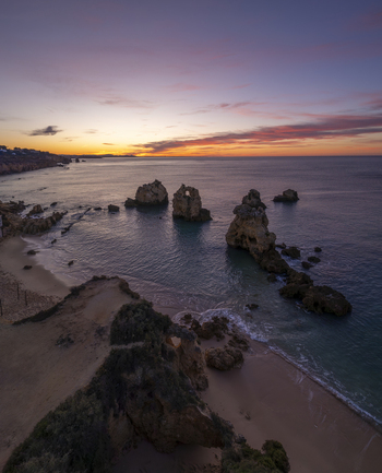 Aerial view of the rock formations at Praia dos Arrifes during a vibrant sunset with calm waters and sandy beach in Faro District Portugal. Aerial view of the rock formations at Praia dos Arrifes during a vibrant sunset with calm waters and sandy beach in Faro District Portugal.