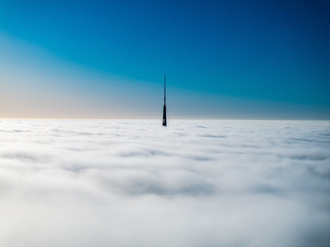 Aerial view of Riga Radio and TV Tower rising above a thick layer of clouds under a clear blue sky in Riga Latvia. Aerial view of Riga Radio and TV Tower rising above a thick layer of clouds under a clear blue sky in Riga Latvia.