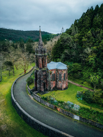 Aerial view of the hauntingly beautiful Capela de Nossa Senhora das Vit&oacute;rias its dark stone contrasting with vibrant green grass Furnas Azores Portugal.
