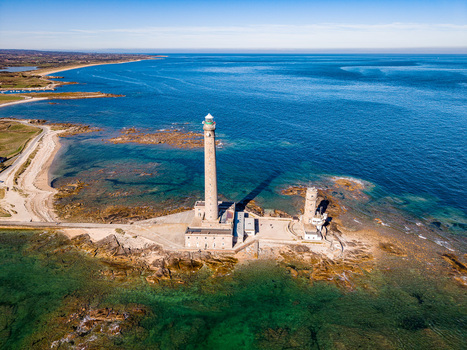 Aerial view of Gatteville Lighthouse standing on a rocky coastline surrounded by clear blue water and coastal scenery in Gatteville le Phare Normandie France.
