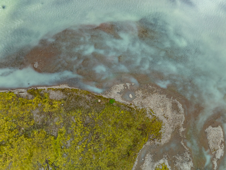 Aerial view of the moss covered terrain and rocky shoreline of Kerlingarfjoll meeting the milky blue glacial waters in Hrunamannahreppur Iceland. Aerial view of the moss covered terrain and rocky shoreline of Kerlingarfjoll meeting the milky blue glacial waters in Hrunamannahreppur Iceland.