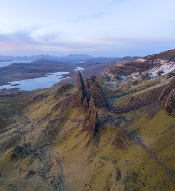 Aerial view of The Storr rocky pinnacles rolling green hills and distant lochs under a soft twilight sky Isle of Skye Scotland United Kingdom. Aerial view of The Storr rocky pinnacles rolling green hills and distant lochs under a soft twilight sky Isle of Skye Scotland United Kingdom.
