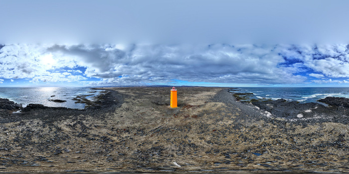 Aerial view of Selvogsviti Lighthouse standing on a rugged volcanic coastline with crashing waves and a dramatic cloudy sky Strandakirkja Sveitarfelagid Olfus Iceland.