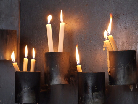 View of lit candles in dark metal holders against a textured wall in Porto Portugal. View of lit candles in dark metal holders against a textured wall in Porto Portugal.