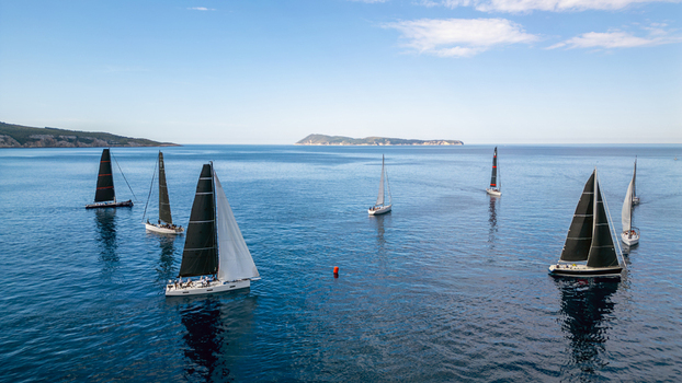 Aerial view of sailboats with black and white sails participating in a regatta on the deep blue Adriatic Sea near Vis Komiza Split Dalmatia County Croatia. Aerial view of sailboats with black and white sails participating in a regatta on the deep blue Adriatic Sea near Vis Komiza Split Dalmatia County Croatia.