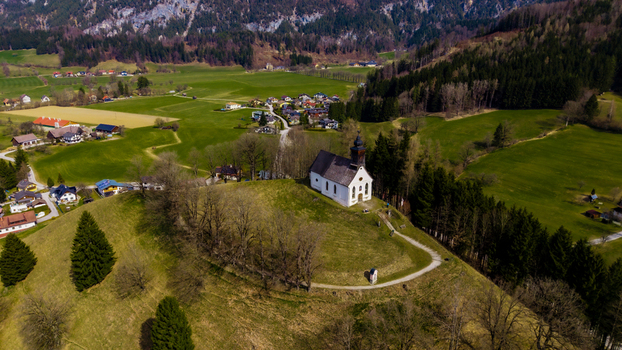 Aerial view of a quaint white church perched atop a hill overlooking the lush Windischgarsten valley a tapestry of green fields and dark forests Windischgarsten Upper Austria Austria. Aerial view of a quaint white church perched atop a hill overlooking the lush Windischgarsten valley a tapestry of green fields and dark forests Windischgarsten Upper Austria Austria.