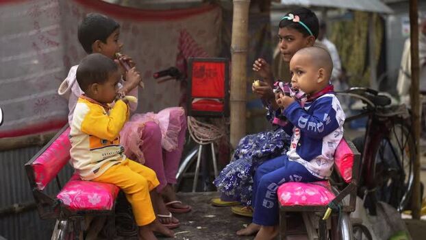 View of children eating bananas on a rickshaw in Bogura Bangladesh.