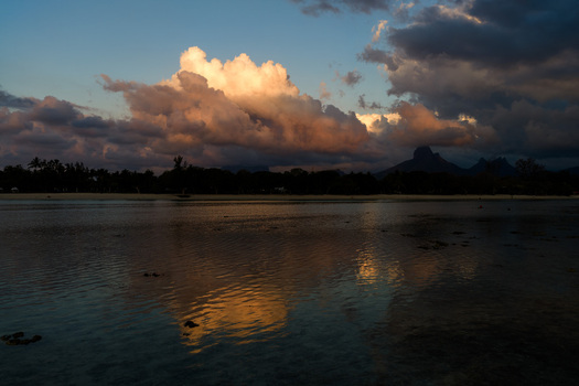 Aerial view of dramatic sunset clouds reflecting on calm coastal waters with silhouetted mountains in the background in Moka District Mauritius. Aerial view of dramatic sunset clouds reflecting on calm coastal waters with silhouetted mountains in the background in Moka District Mauritius.