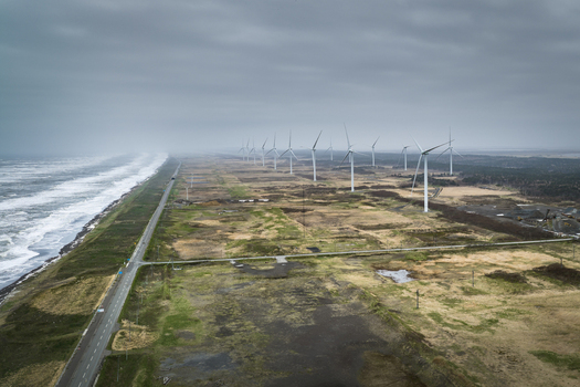 Aerial view of a wind farm with multiple turbines standing along the rugged coastline and a road running parallel to the sea in Wakkanai Hokkaido Japan.