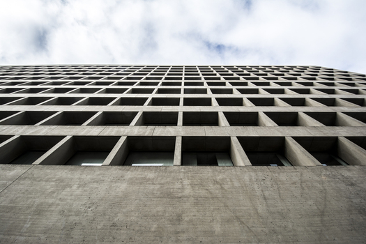 View of the grid like concrete facade of a modern building in Downtown looking up towards a cloudy sky Lincoln Nebraska United States.