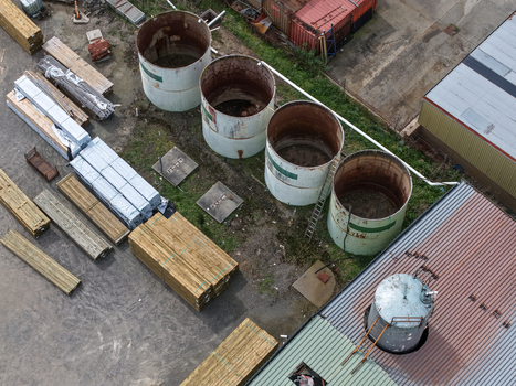 Melbourne VIC Australia 25 September 2026 Aerial view of an industrial site featuring large cylindrical storage tanks stacks of timber and factory buildings.