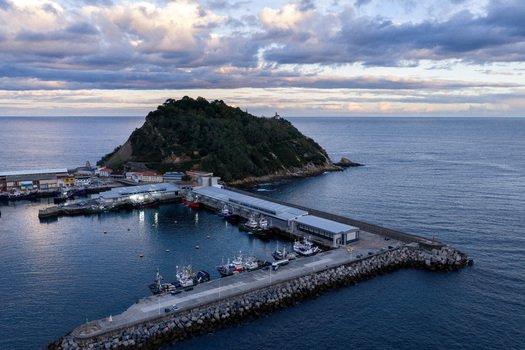 Aerial view of Getariako portua with fishing boats docked in the harbor stone breakwaters and the coastal landscape of Getaria Basque Country Spain. Aerial view of Getariako portua with fishing boats docked in the harbor stone breakwaters and the coastal landscape of Getaria Basque Country Spain.