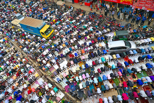 Tongi Dhaka Division Bangladesh 31 January 2025 Aerial view of Tongi Ijtema Maidan with a large crowd of worshippers praying on mats amidst parked vehicles and urban surroundings.