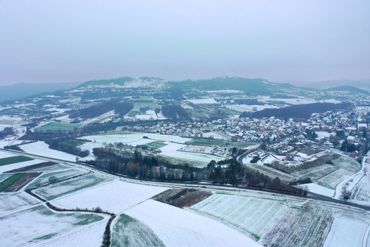 Aerial view of the Walberla mountain overlooking snow covered fields and the village of Kirchehrenbach Bavaria Germany.