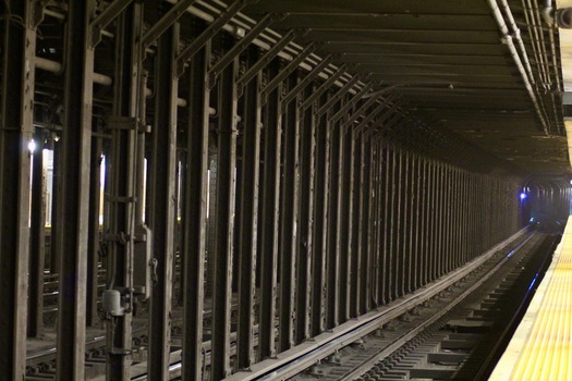 View of a subway tunnel with industrial steel support columns train tracks and a platform edge Queens County New York United States.