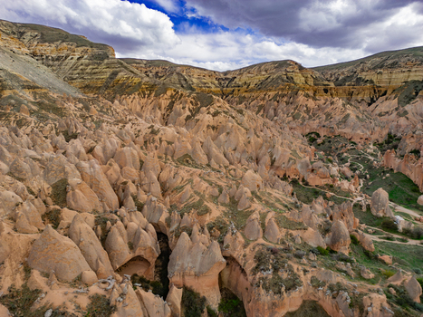 Aerial view of Zelve Vadisi featuring unique fairy chimneys and rugged rock formations under a cloudy sky in Goreme Nevsehir Turkiye. Aerial view of Zelve Vadisi featuring unique fairy chimneys and rugged rock formations under a cloudy sky in Goreme Nevsehir Turkiye.
