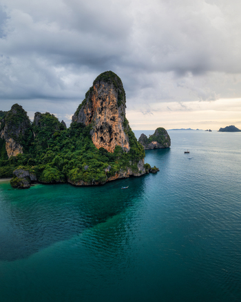 Aerial view of Railay Beach featuring dramatic limestone cliffs rising from turquoise waters with lush vegetation and a small boat in Ao Nang Krabi Thailand. Aerial view of Railay Beach featuring dramatic limestone cliffs rising from turquoise waters with lush vegetation and a small boat in Ao Nang Krabi Thailand.
