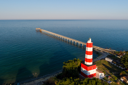 Aerial view of the red and white Saints Constantine and Helena Lighthouse and long pier extending into the Black Sea in Saints Constantine and Helena Varna Bulgaria.