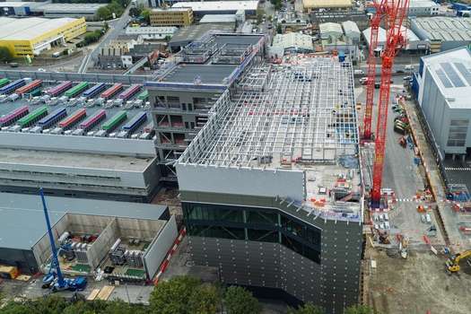 Aerial view of a data center construction site featuring a steel frame structure and a red crane in the United Kingdom.
