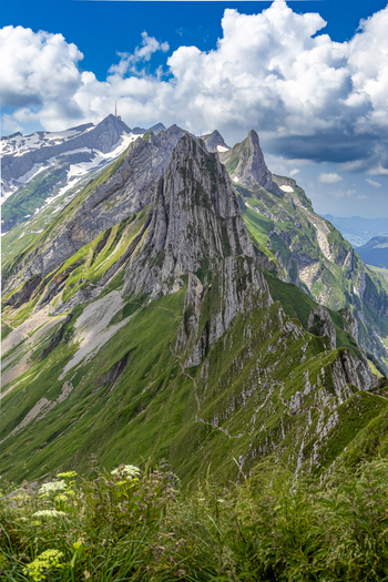 Aerial view of a sharp rocky mountain ridge with green slopes under a blue sky with scattered clouds Schwende Rüte Appenzell Innerrhoden Switzerland. Aerial view of a sharp rocky mountain ridge with green slopes under a blue sky with scattered clouds Schwende Rüte Appenzell Innerrhoden Switzerland.