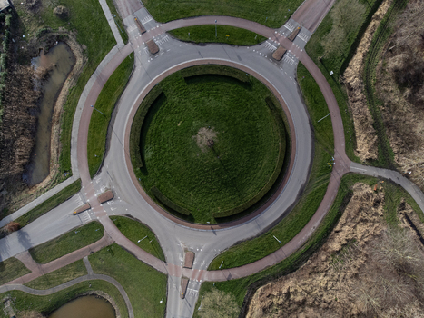 Aerial view of a roundabout with a circular green grass area in the center surrounded by gray roads and green grass Overgooi Flevoland Netherlands. Aerial view of a roundabout with a circular green grass area in the center surrounded by gray roads and green grass Overgooi Flevoland Netherlands.