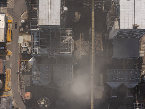 Aerial view of an industrial facility with metal structures pipes and storage tanks emitting steam in Bajos de Haina San Cristobal Province Dominican Republic.