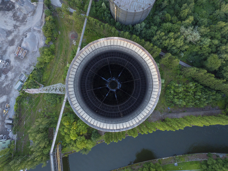 Aerial view of the iconic I.M. cooling tower in an industrial landscape with surrounding trees and a river in Charleroi Wallonia Belgium.