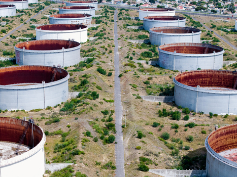 Aerial view of large industrial oil storage tanks in Milnerton featuring weathered metal surfaces and surrounding sparse vegetation in Cape Town Western Cape South Africa. Aerial view of large industrial oil storage tanks in Milnerton featuring weathered metal surfaces and surrounding sparse vegetation in Cape Town Western Cape South Africa.